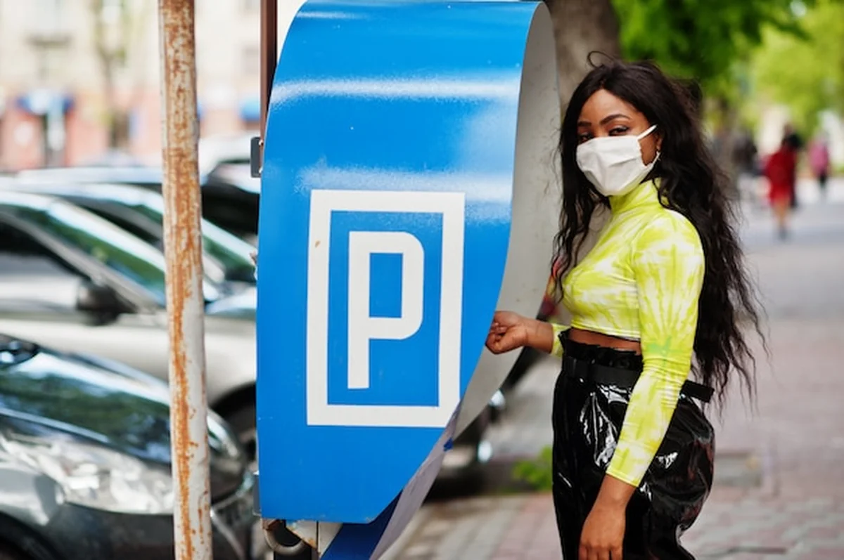 African American kobieta z maską na twarzy przy terminalu parkingowym