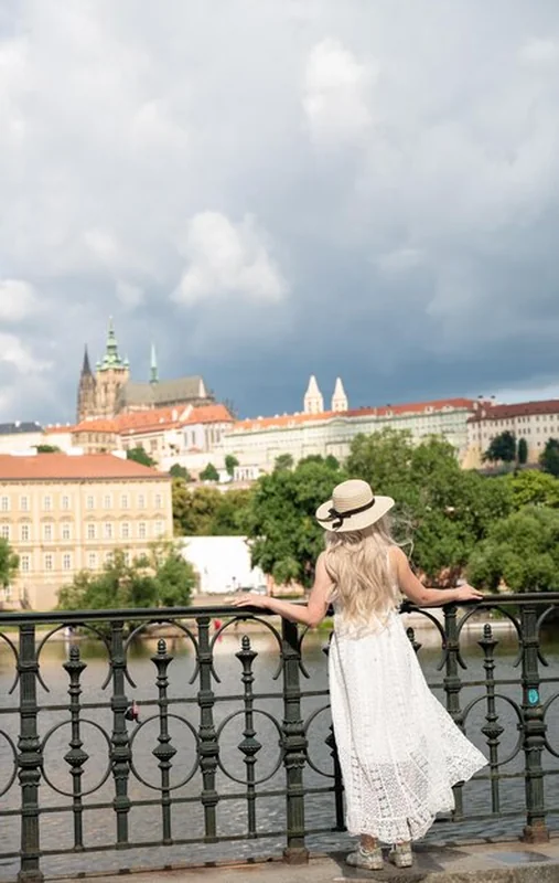 Młoda turystka pozująca przy ogrodzeniu nad rzeką Włtawą w Pradze
