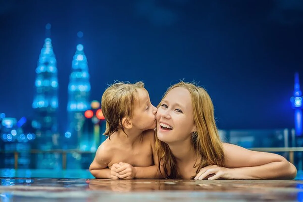Matka i syn w odkrytym basenie z widokiem na miasto w nocy